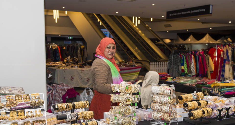 A woman in a hijab is standing in front of a table full of bracelets.