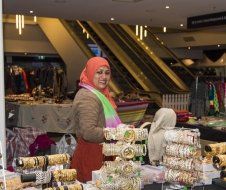 A woman in a hijab is selling bracelets in a store.