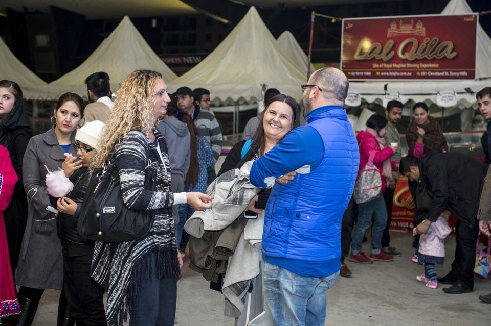 A group of people are standing in front of a food stand.