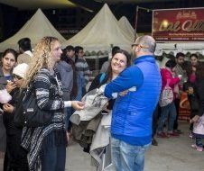A group of people are standing in front of a tent talking to each other.