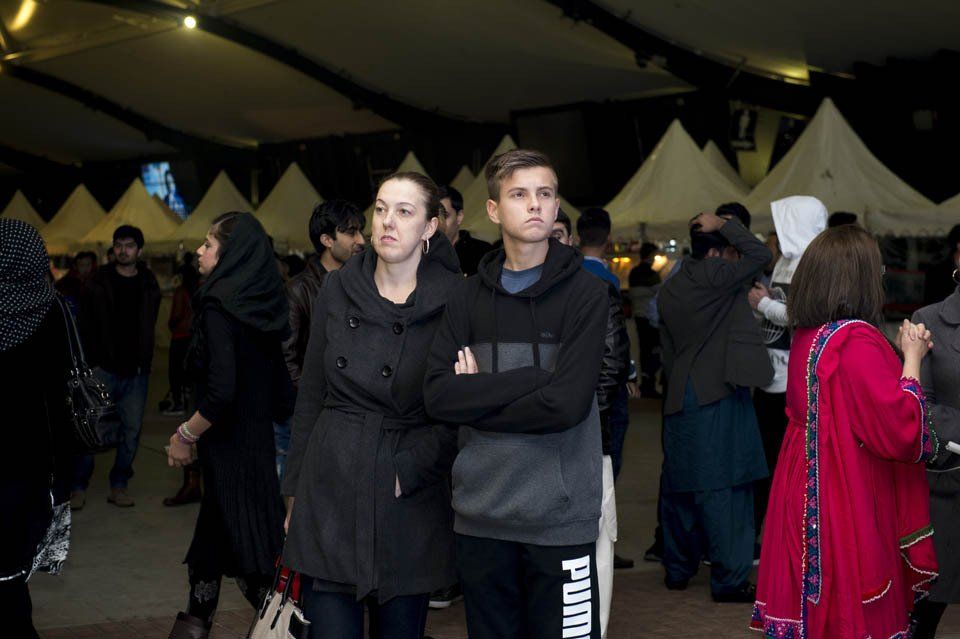 A man and a woman are standing in a crowd wearing puma pants