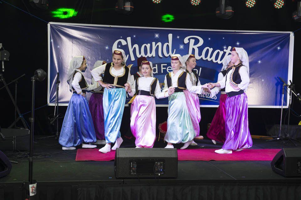 A group of people are dancing on a stage in front of a banner that says chand raat