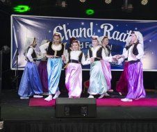 A group of people are dancing on a stage in front of a banner.