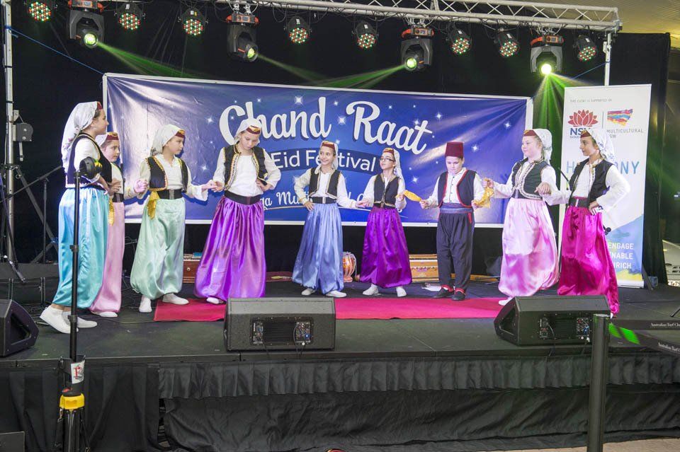 A group of people are dancing on a stage in front of a banner that says chand raat