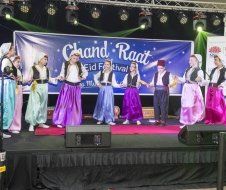 A group of people are dancing on a stage in front of a banner.