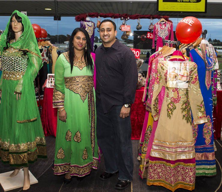 A man and woman standing in front of a display of dresses