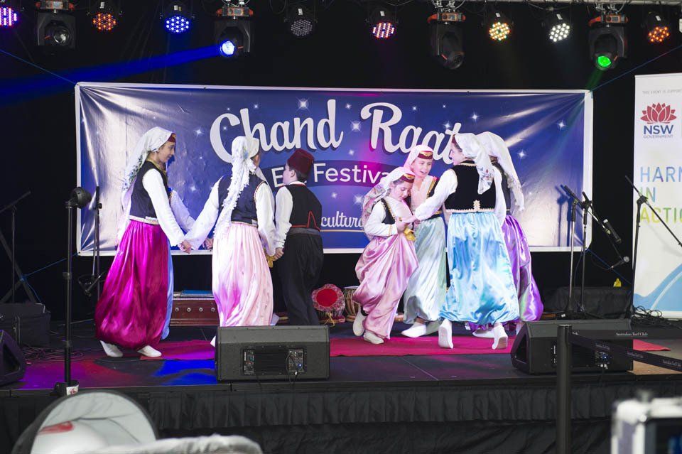 A group of people are dancing on a stage in front of a banner that says chand raga festival