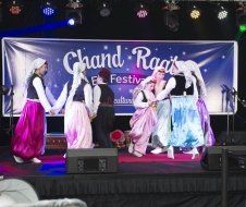 A group of people are dancing on a stage at a festival.