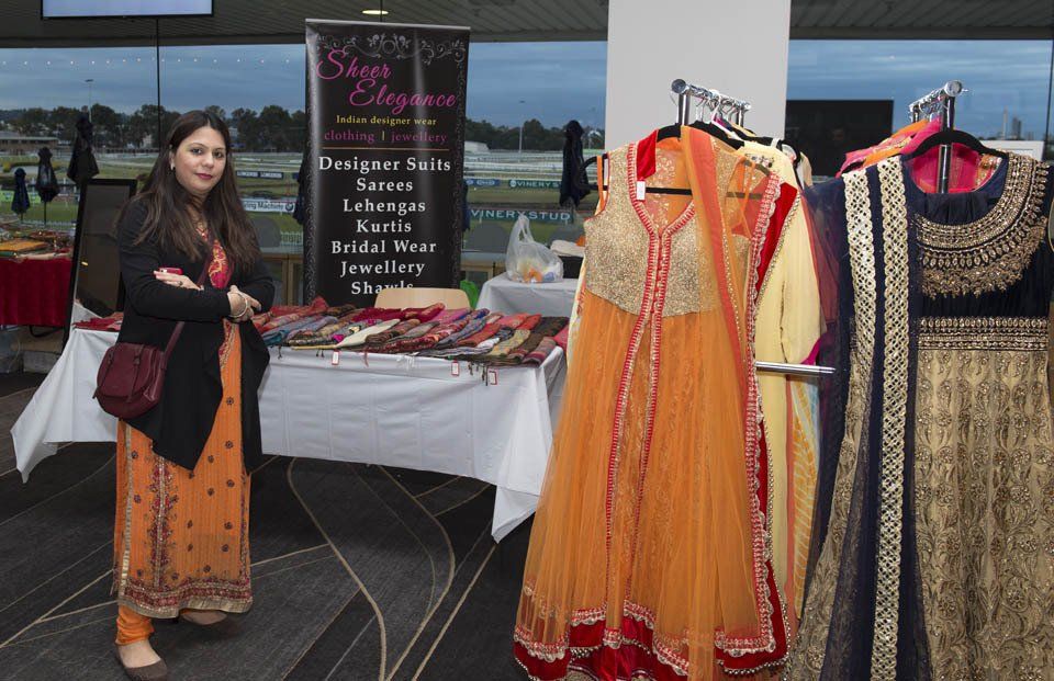 A woman is standing in front of a table with clothes on it.