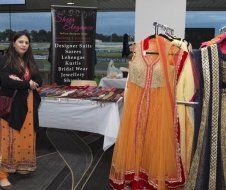 A woman is standing in front of a table with clothes on it.