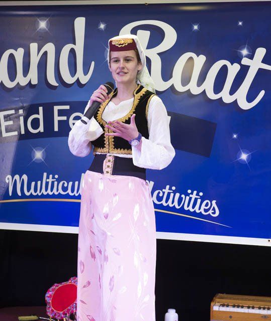 A woman stands in front of a sign that says 