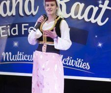 A woman is standing in front of a sign holding a microphone.