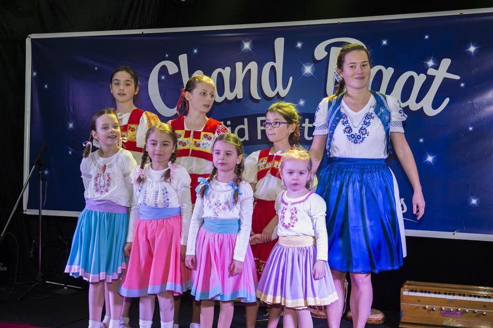 A group of young girls are posing for a picture in front of a sign that says chand that.