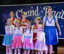 A group of young girls are standing on a stage in front of a sign.