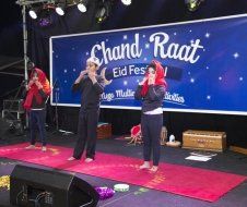 A group of people are standing on a stage in front of a large sign.