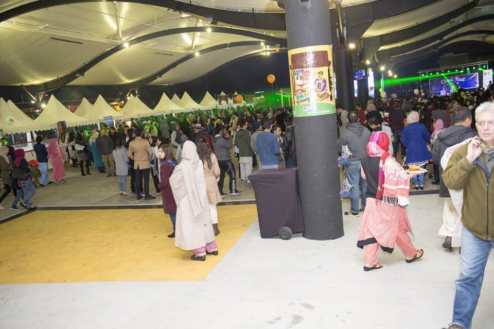 A crowd of people are gathered in a large room with a sign that says ' coca cola ' on it.