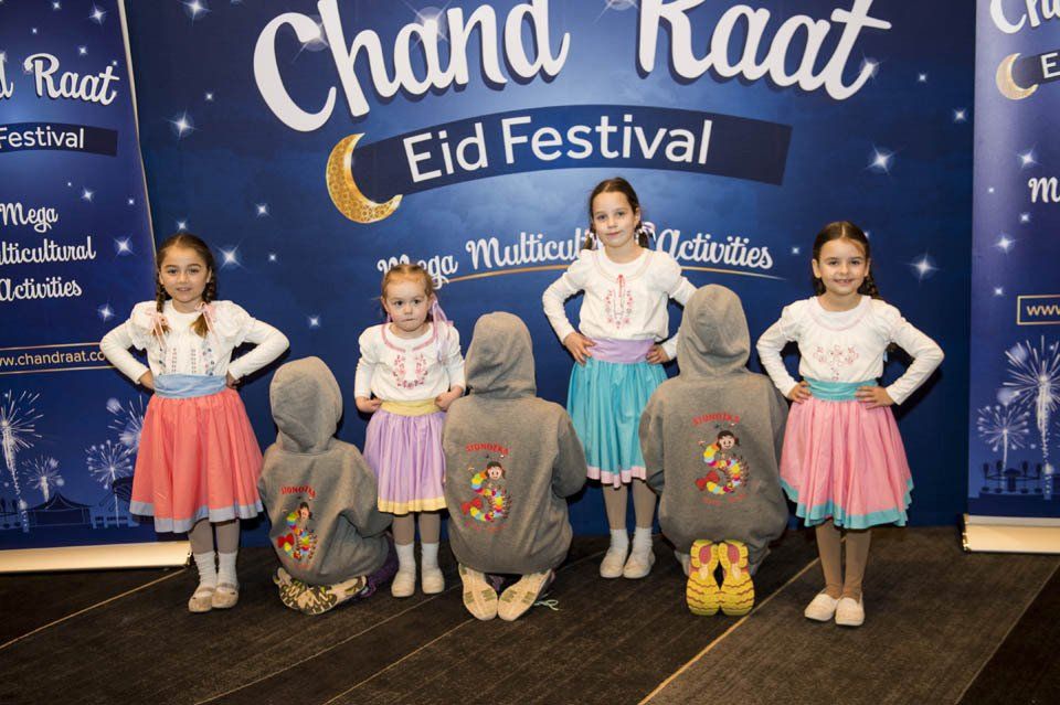 A group of children standing in front of a sign that says chand raat eid festival