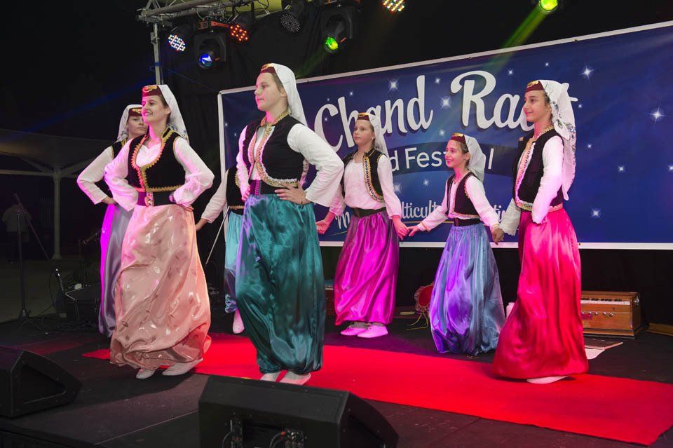 A group of women in colorful dresses are dancing on a stage.