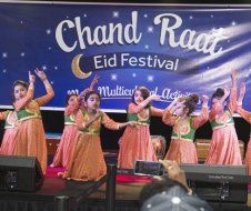 A group of young girls are dancing on a stage at a festival.