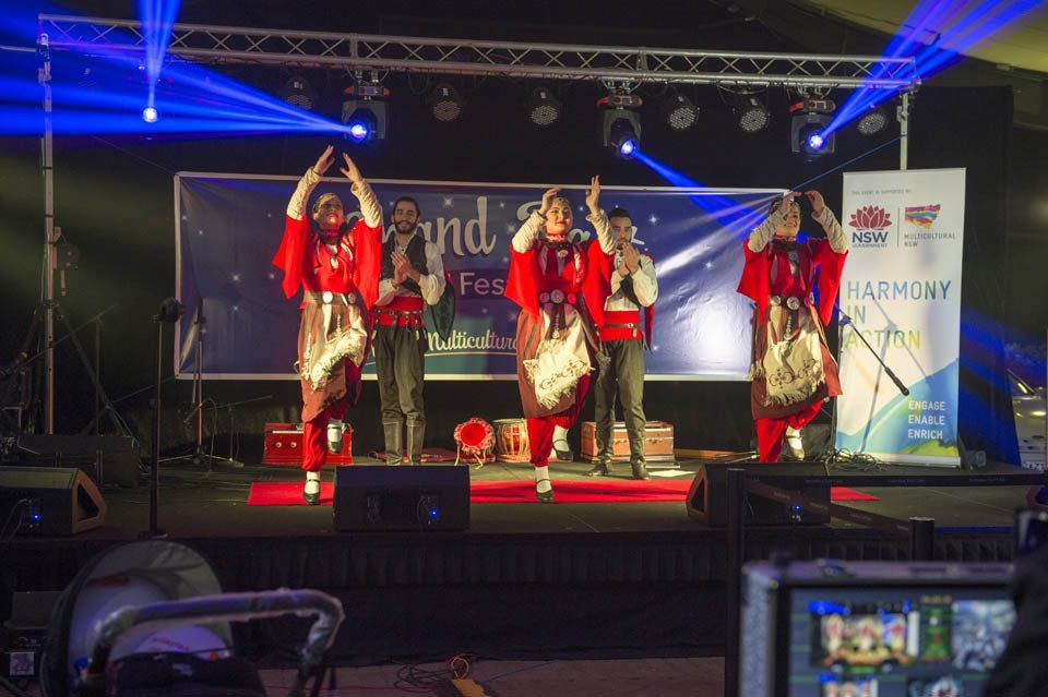 A group of people are dancing on a stage at a concert.