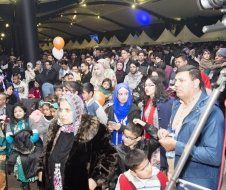 A large group of people are standing in a room with balloons.