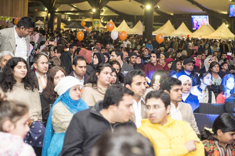 A crowd of people are gathered in a room with tents and balloons.