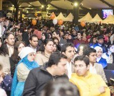 A crowd of people are gathered in a room with tents and balloons.