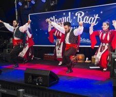 A group of people are dancing on a stage in front of a sign that says chand raat.