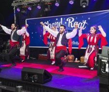 A group of people are dancing on a stage in front of a sign.