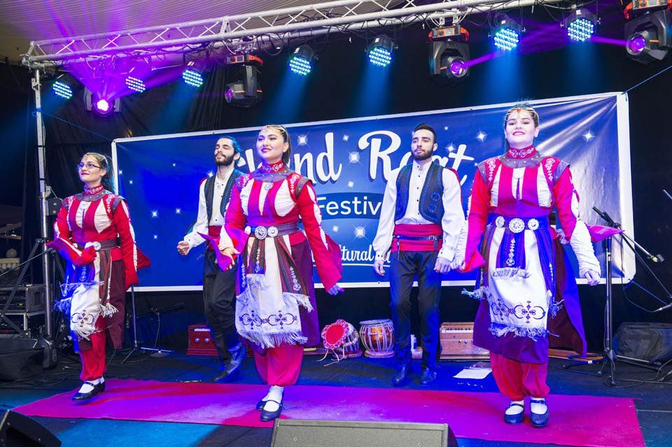 A group of people are dancing on a stage at a festival.