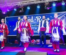 A group of people are dancing on a stage at a festival.