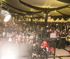 A large crowd of people are sitting in a large room watching a concert.