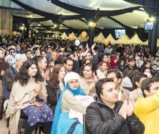 A large group of people are sitting in a room applauding.