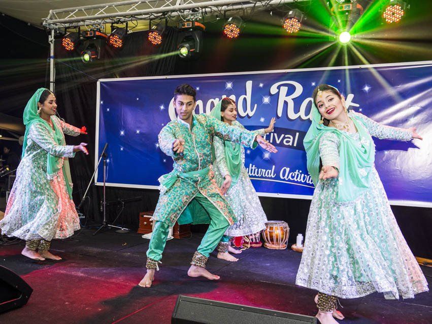 A group of people are dancing on a stage at a festival.