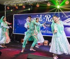 A group of people are dancing on a stage in front of a sign.