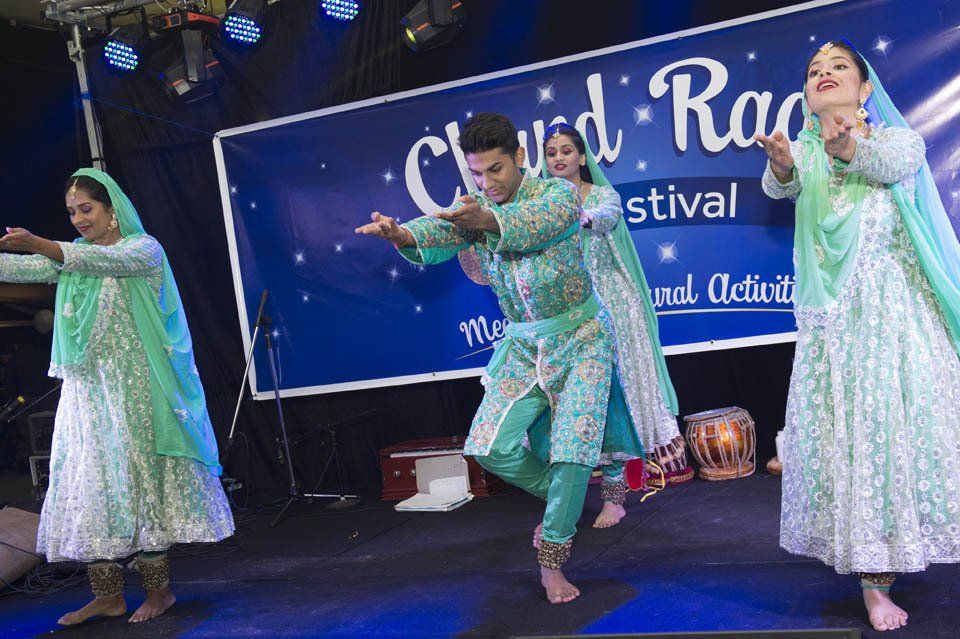 A group of people are dancing in front of a sign that says cloud road festival