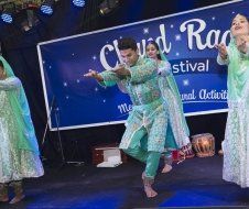 A group of people are dancing on a stage in front of a sign.