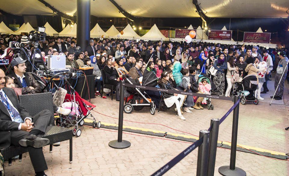 A large crowd of people are gathered in a tent.