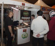 A group of people are standing around a food stand.