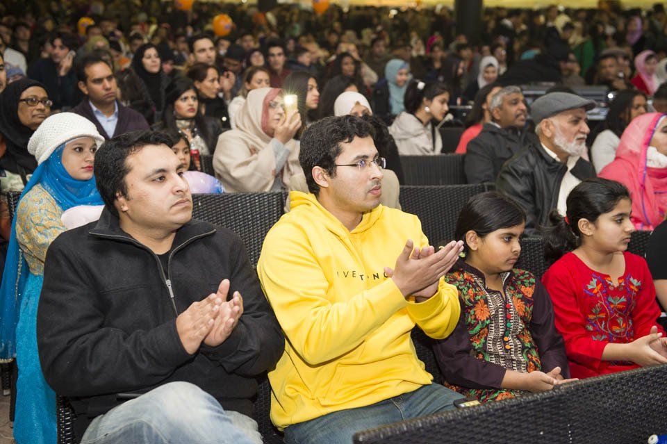 A crowd of people are sitting in a stadium clapping their hands.