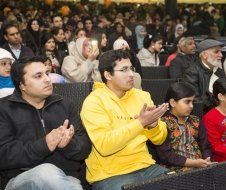 A crowd of people are sitting in a theater applauding.