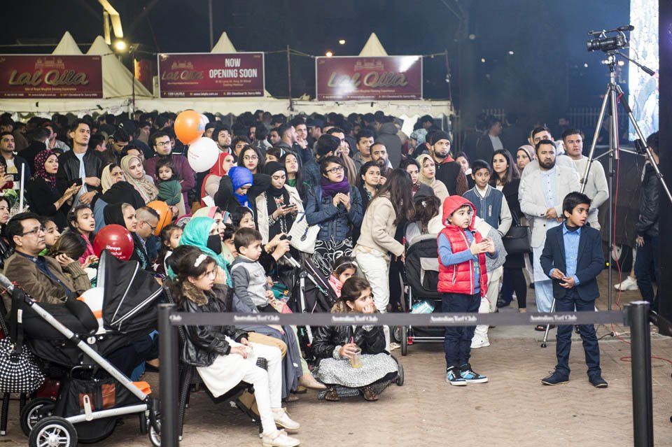A crowd of people sitting in stroller watching a concert.