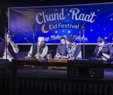 A group of people are sitting on a stage playing instruments.