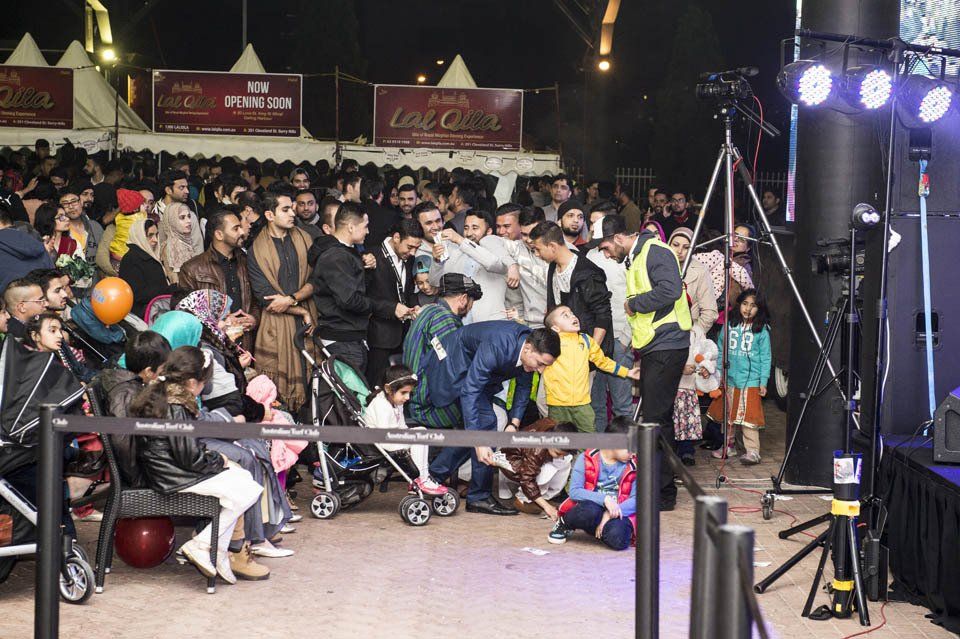 A crowd of people are gathered in front of a stage.