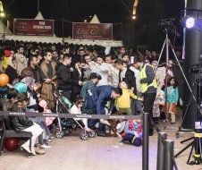 A large group of people are standing around a stage at a concert.