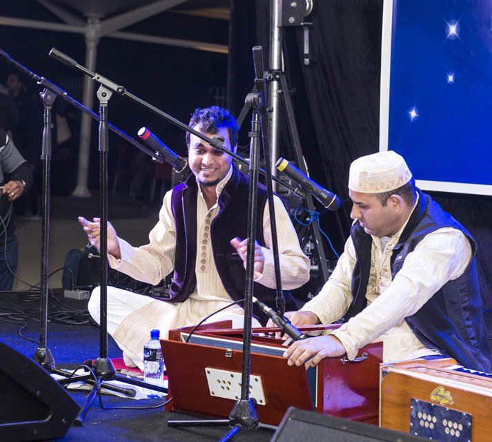 Two men are sitting on a stage playing instruments