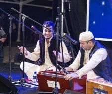 Two men are playing instruments on a stage in front of microphones.