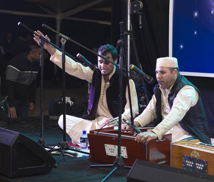 Two men are playing musical instruments in front of microphones