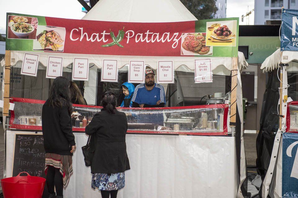 Two women are standing in front of a food stand called chat pataaz.