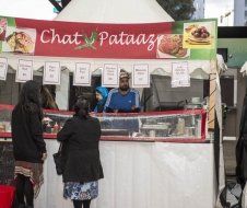 A man is standing behind a counter at a food stand.